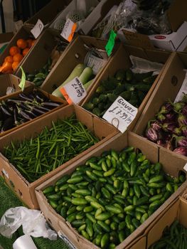 A vibrant selection of fresh vegetables on display at a local market stall, including cucumbers and eggplants.. pexels, vibra