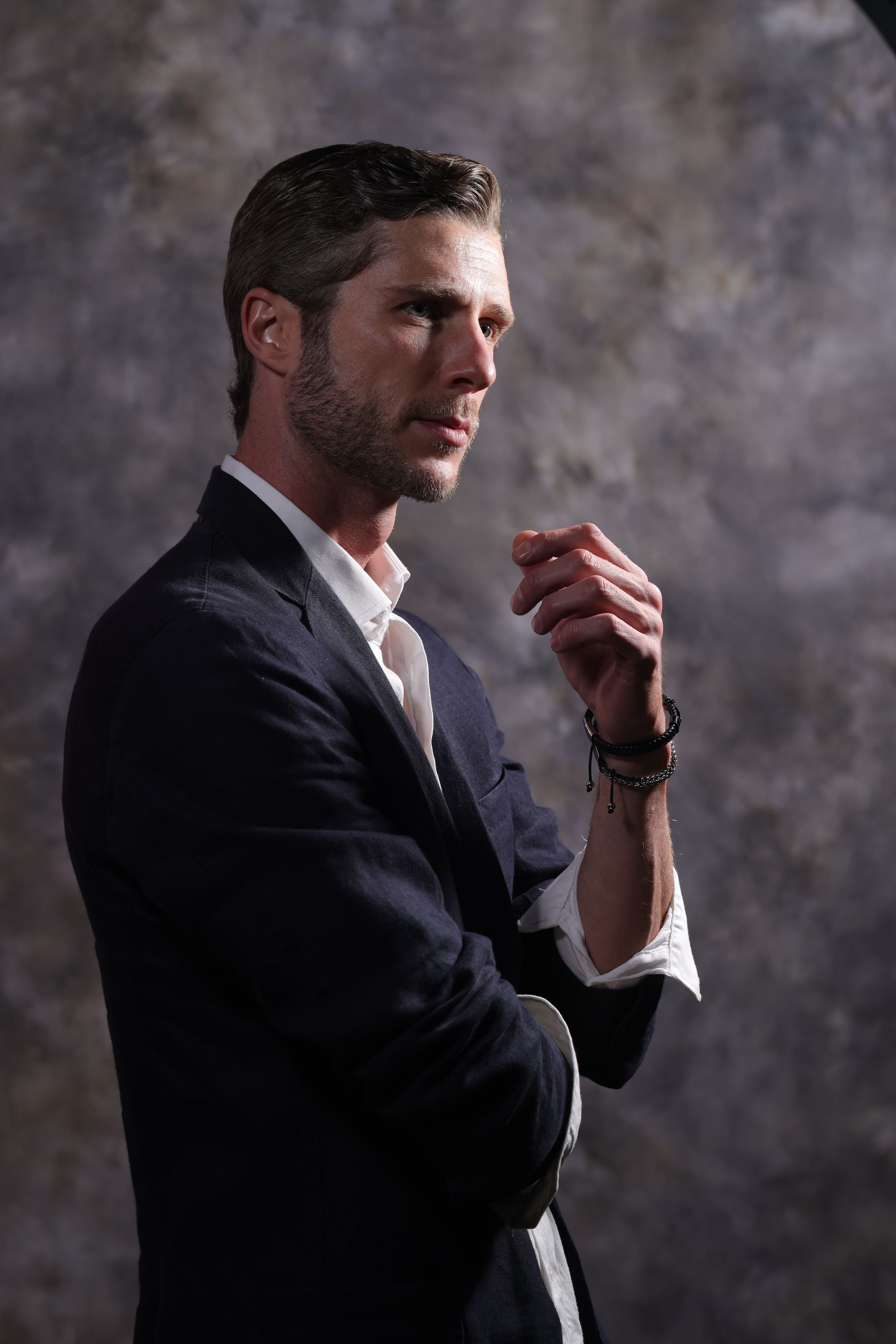 Portrait of a thoughtful man in a suit against a textured background.