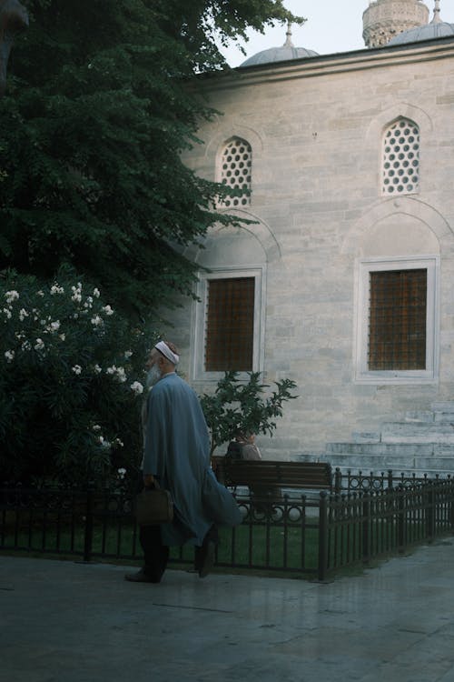 Man Walking near Mosque Wall