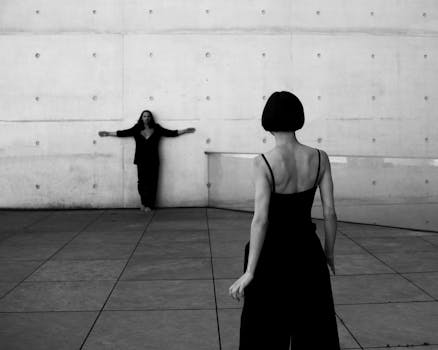 Stylish couple posing in black attire against a modern wall in Berlin, Germany.