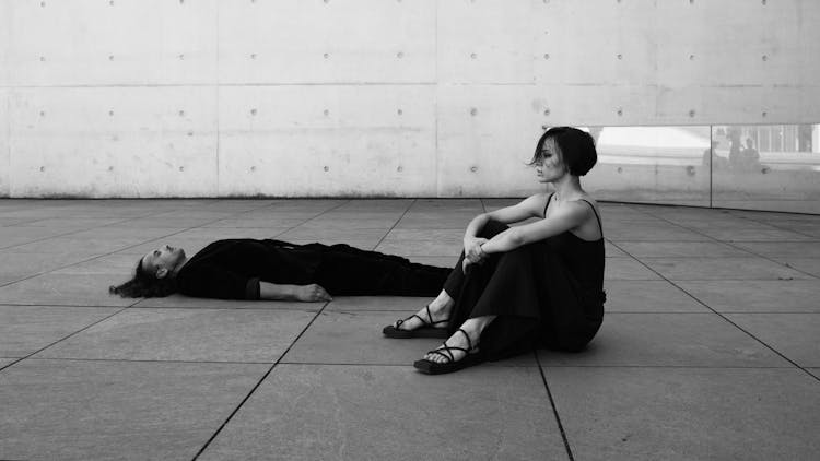 Couple Sitting On Ground Near Modern Building