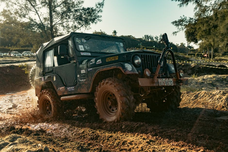 A rugged jeep charges through a muddy off-road terrain, showcasing power and adventure.