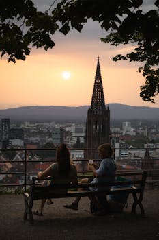 Couple enjoying a sunset view over Freiburg with the cathedral in the background.