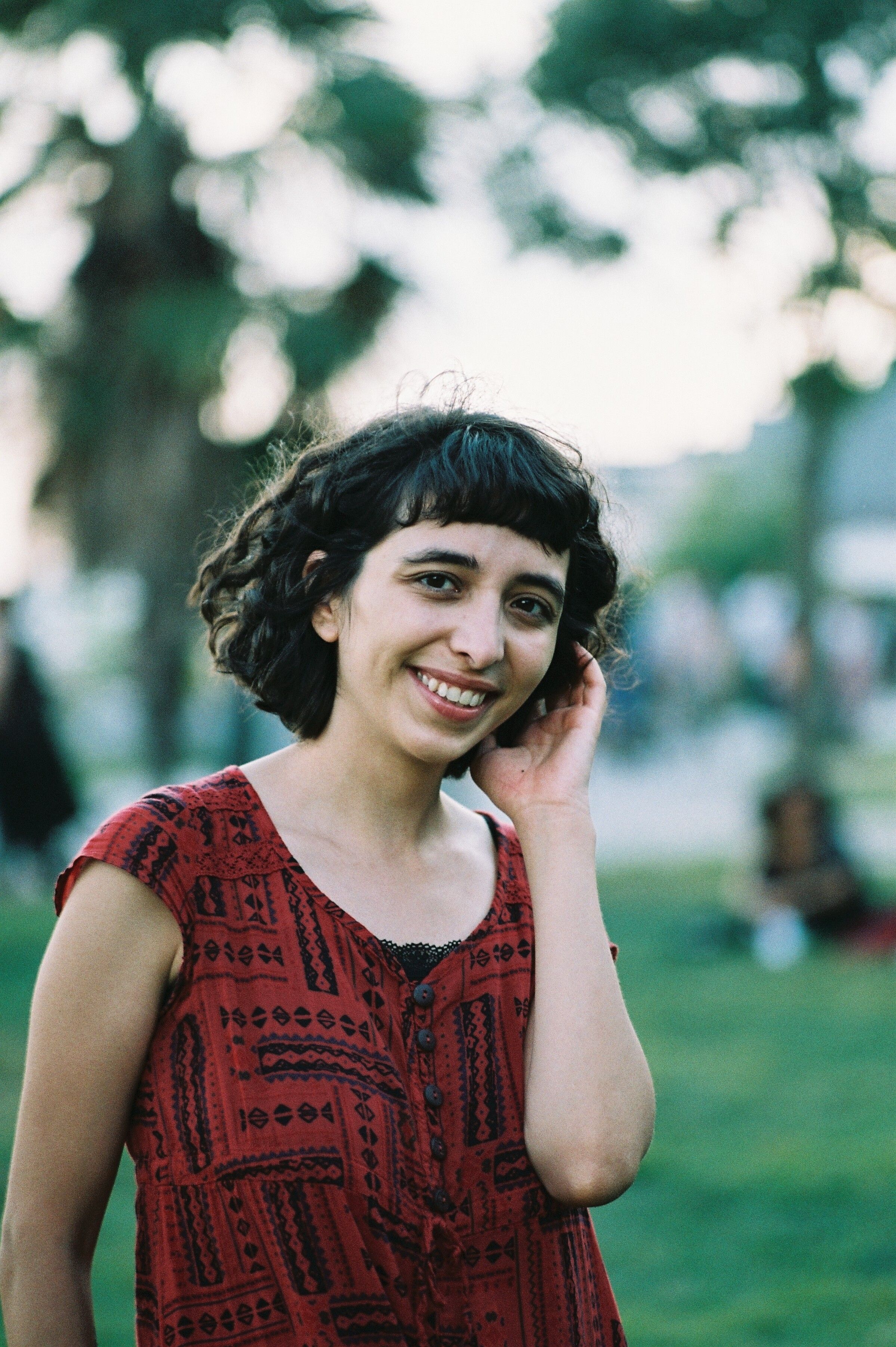Young woman smiling warmly in an outdoor park during summer.