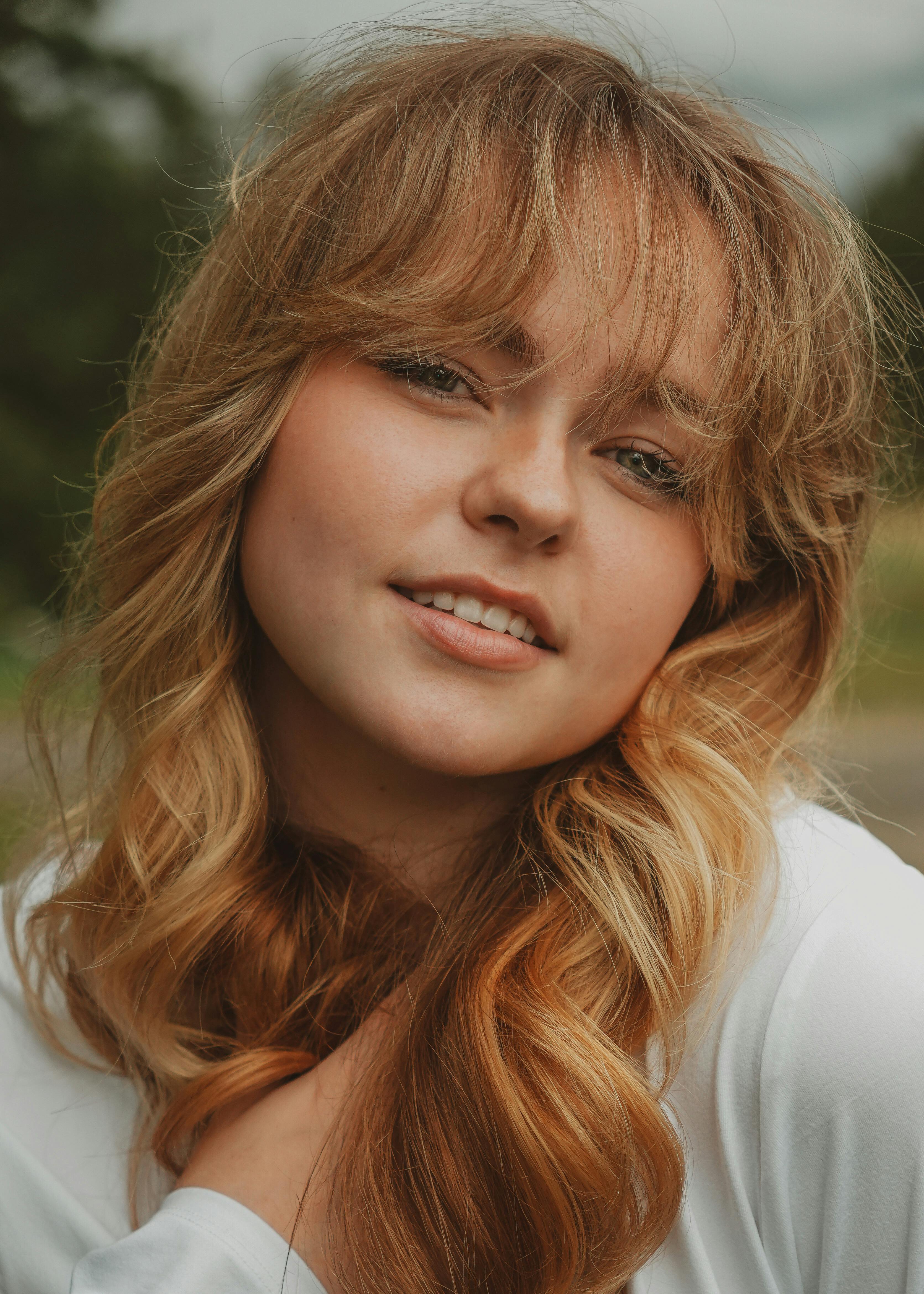 A captivating portrait of a smiling young blonde woman taken outdoors in Maine, USA.
