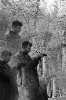 Artistic black and white shot of a photographer in a birch forest using a creative multiple exposure technique.