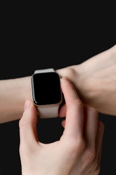 Close-up of hand adjusting a modern smartwatch with black screen.