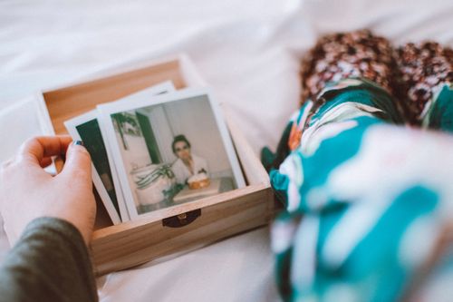 Free A woman reminisces as she browses vintage photographs indoors. Stock Photo