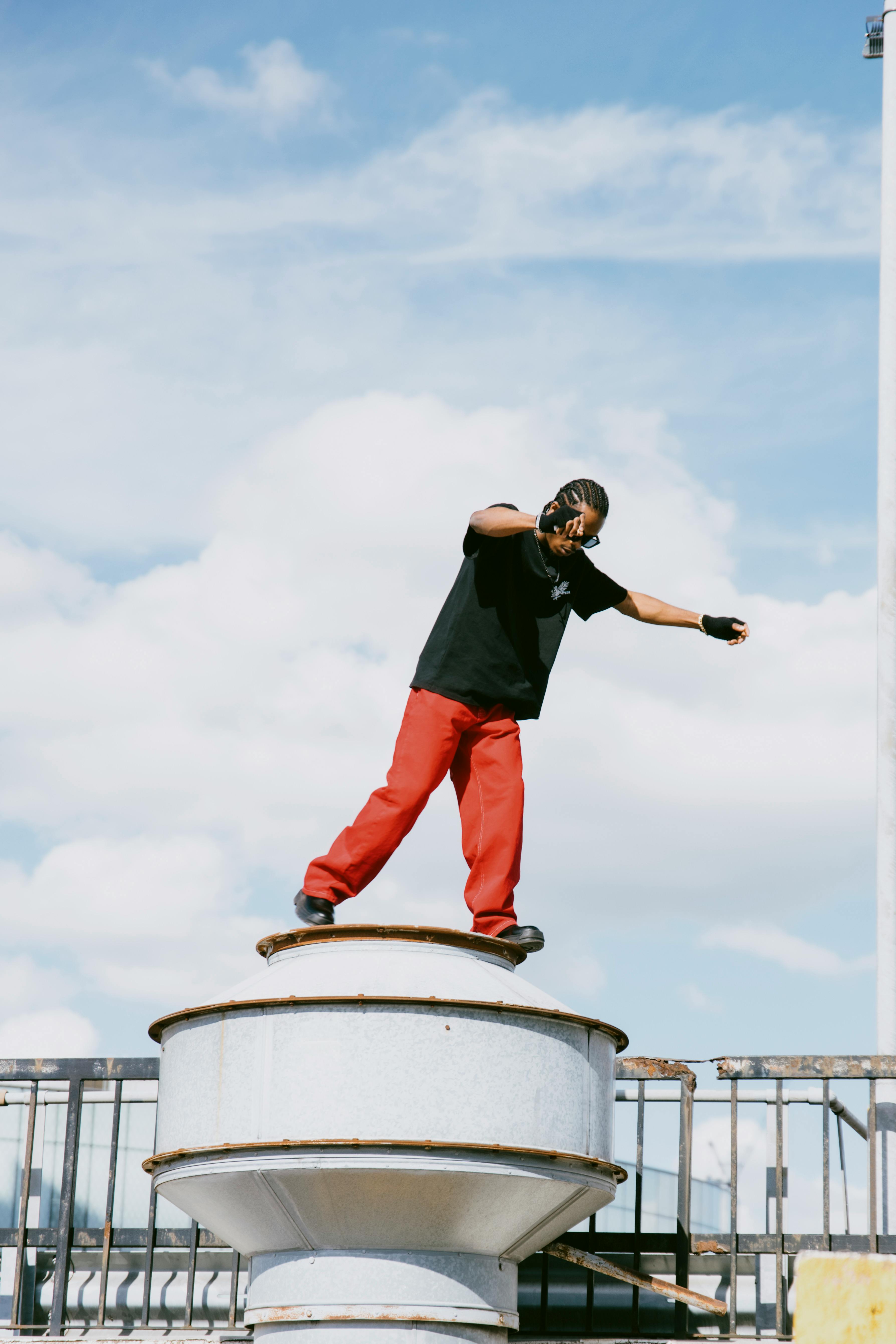 Man posing confidently on a rooftop with clear blue sky.