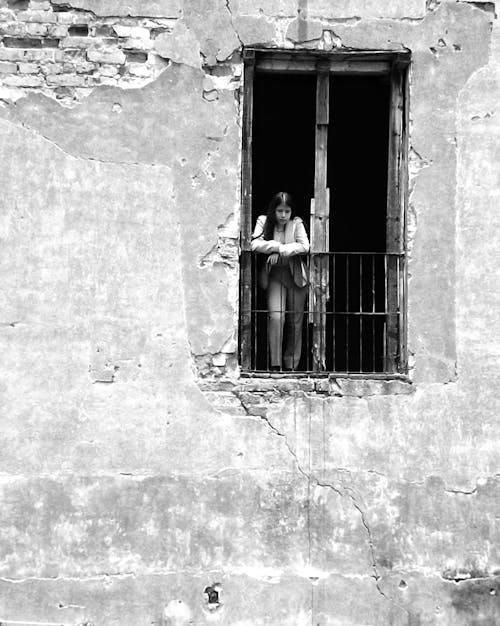 Woman Standing in Windows in Damaged Building