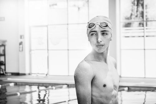 Free Monochrome image of a shirtless teenage swimmer with goggles in an indoor pool. Stock Photo