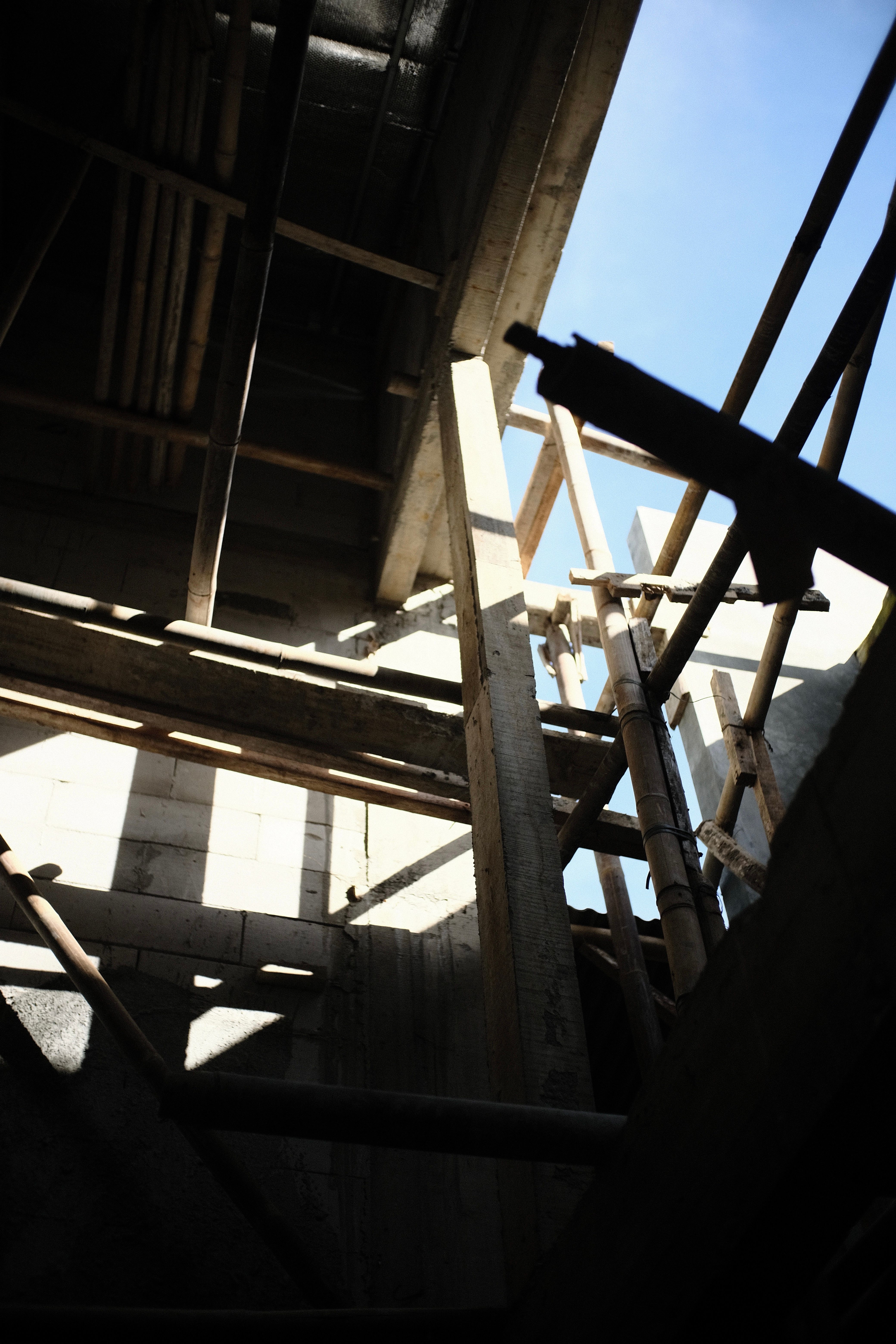 Sunlit abandoned construction site with wooden scaffolding and concrete walls.