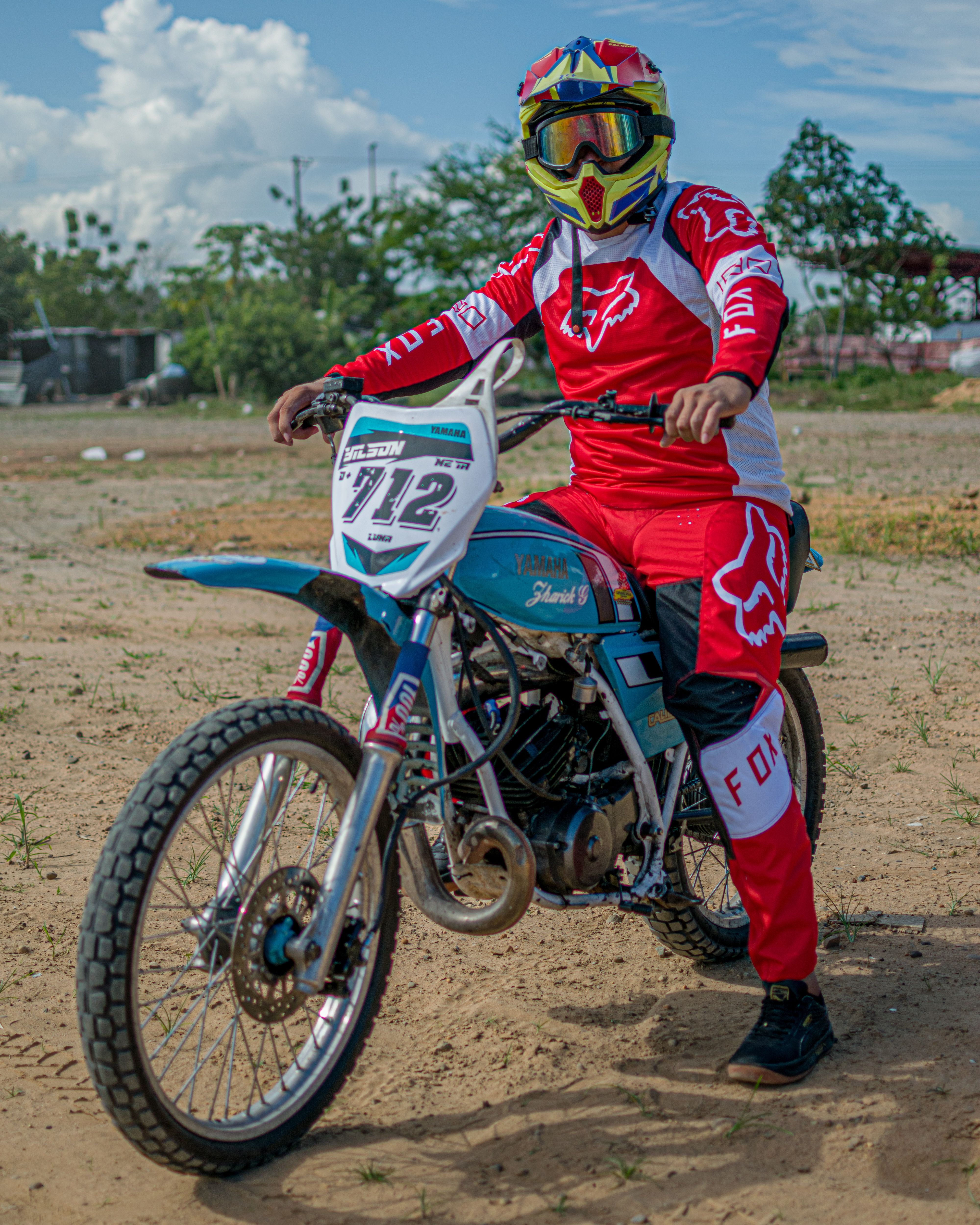 Motocross rider in vibrant gear ready for action on a dirt track.