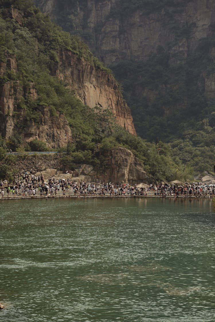 A Crowd Standing On The Shore Of A Body Of Water In The Valley