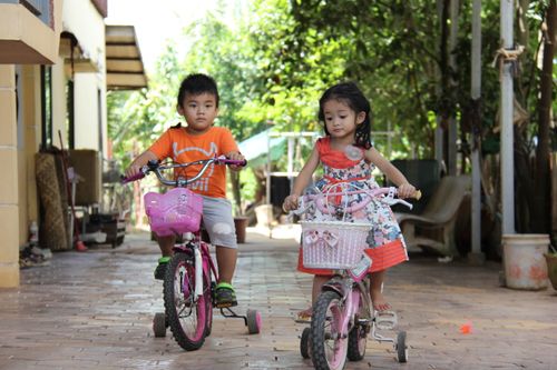 Free Two young children enjoy riding bicycles outdoors in Krong Siem Reap, Cambodia. Stock Photo