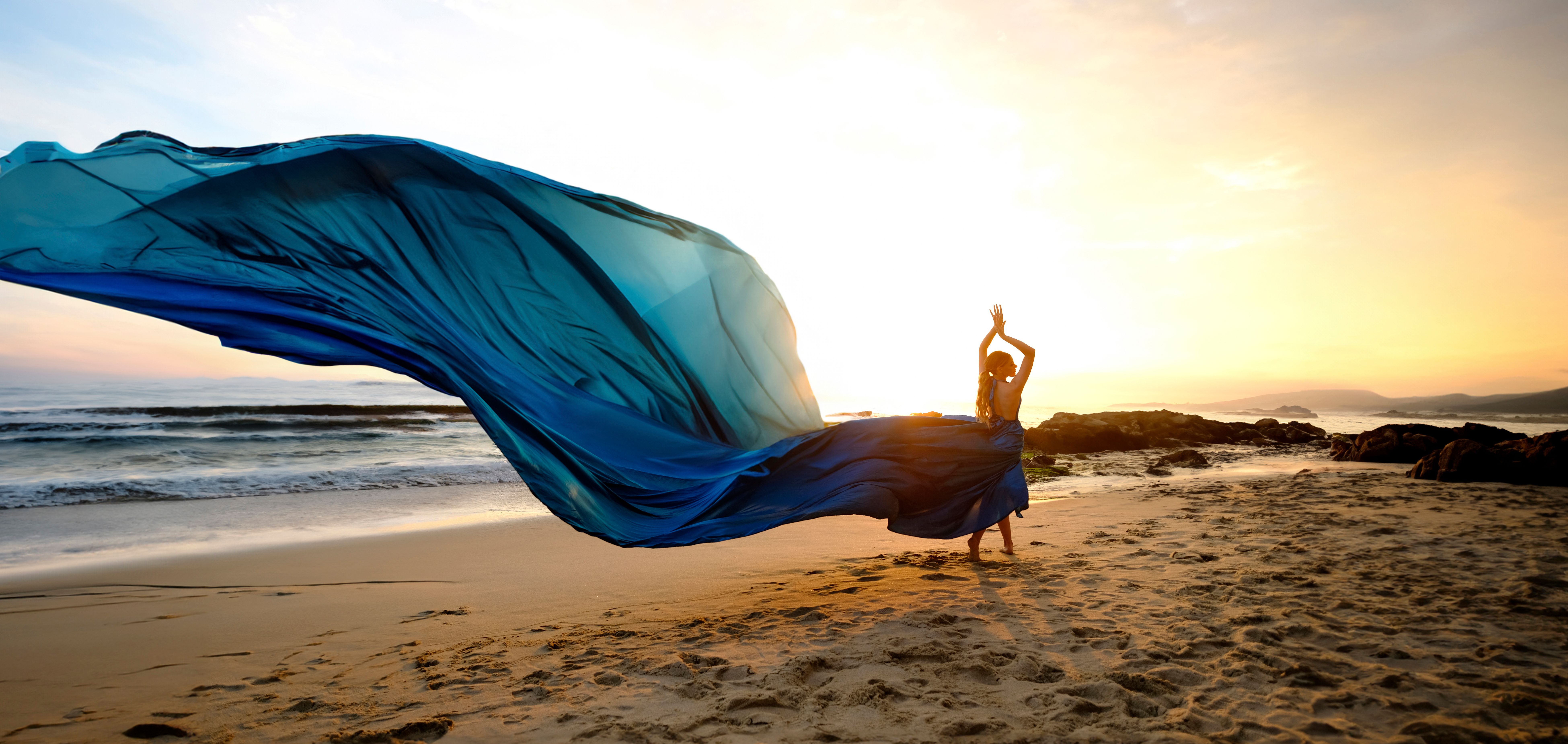 Woman in Long, Blue Dress Posing on Sea Shore at Sunset  Free Stock Photo