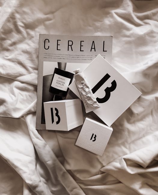 Minimalist arrangement of luxury cosmetic boxes and a magazine on white fabric, ideal for a relaxed lifestyle.