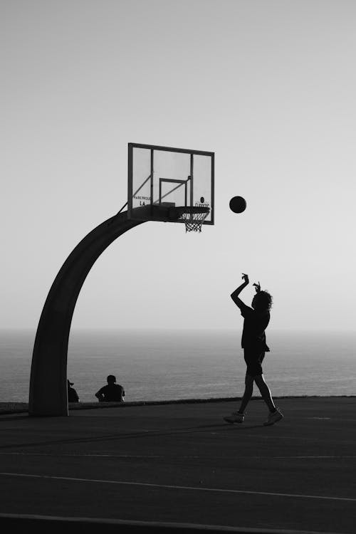 Silhouette of a Man Throwing a Basketball into the Hoop
