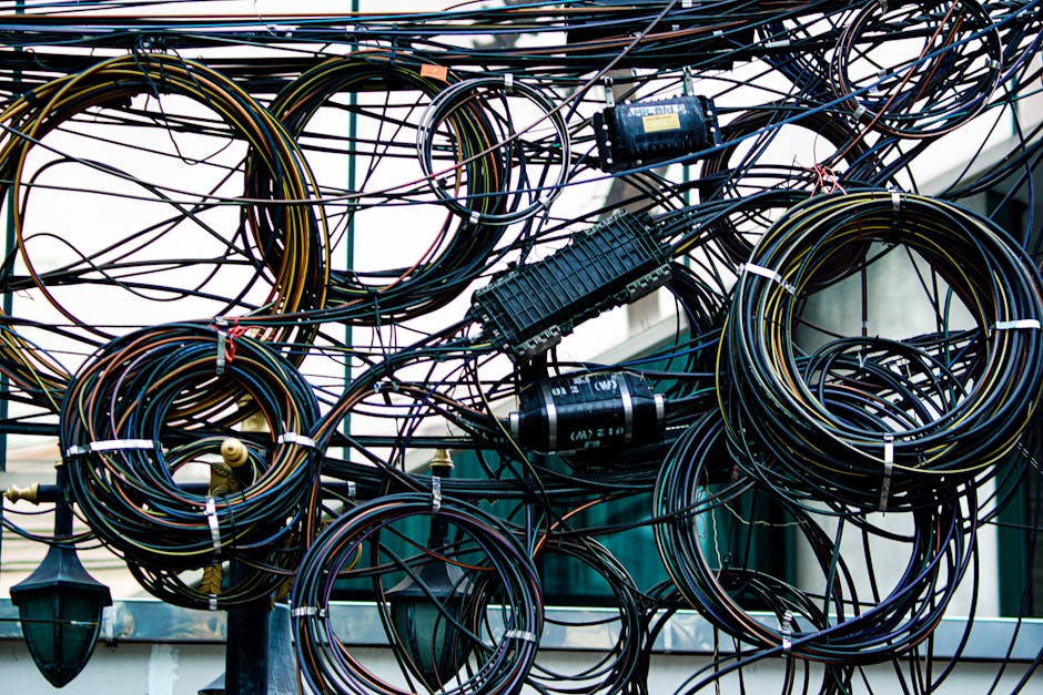 Intricate network of tangled power and communication cables outdoors.