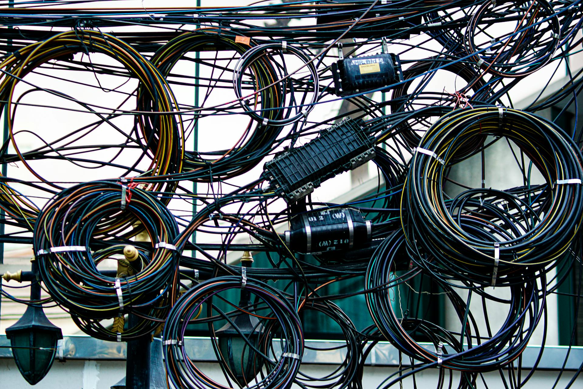 Intricate network of tangled power and communication cables outdoors.