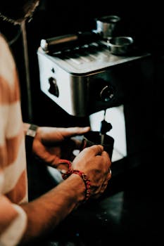 Close-up of a man pouring coffee from an espresso machine in a cafe, Shiraz, Iran.