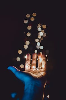 一只握着发光串灯的手的特写镜头，背景带有美丽的散景效果