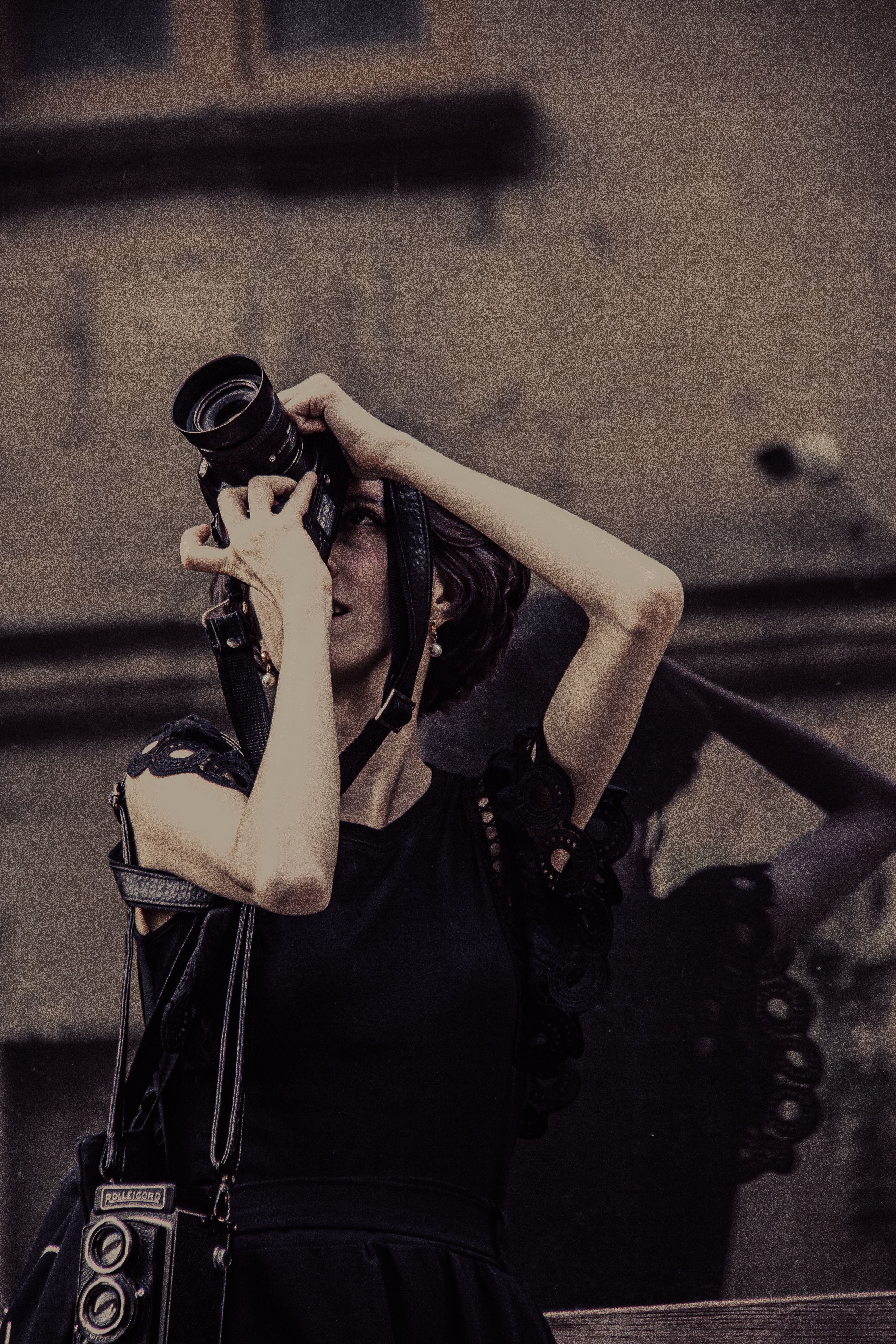 Artistic portrait of a woman using a camera in an urban environment, reflecting creativity.