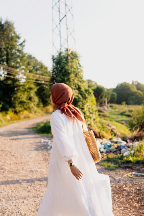 Woman in Hijab and White Clothes Walking on Dirt Road