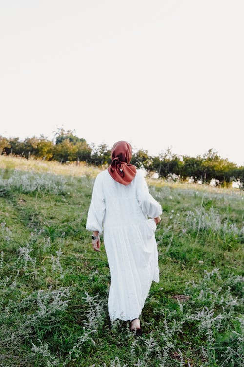 Woman in Hijab and White Clothes Walking on Meadow