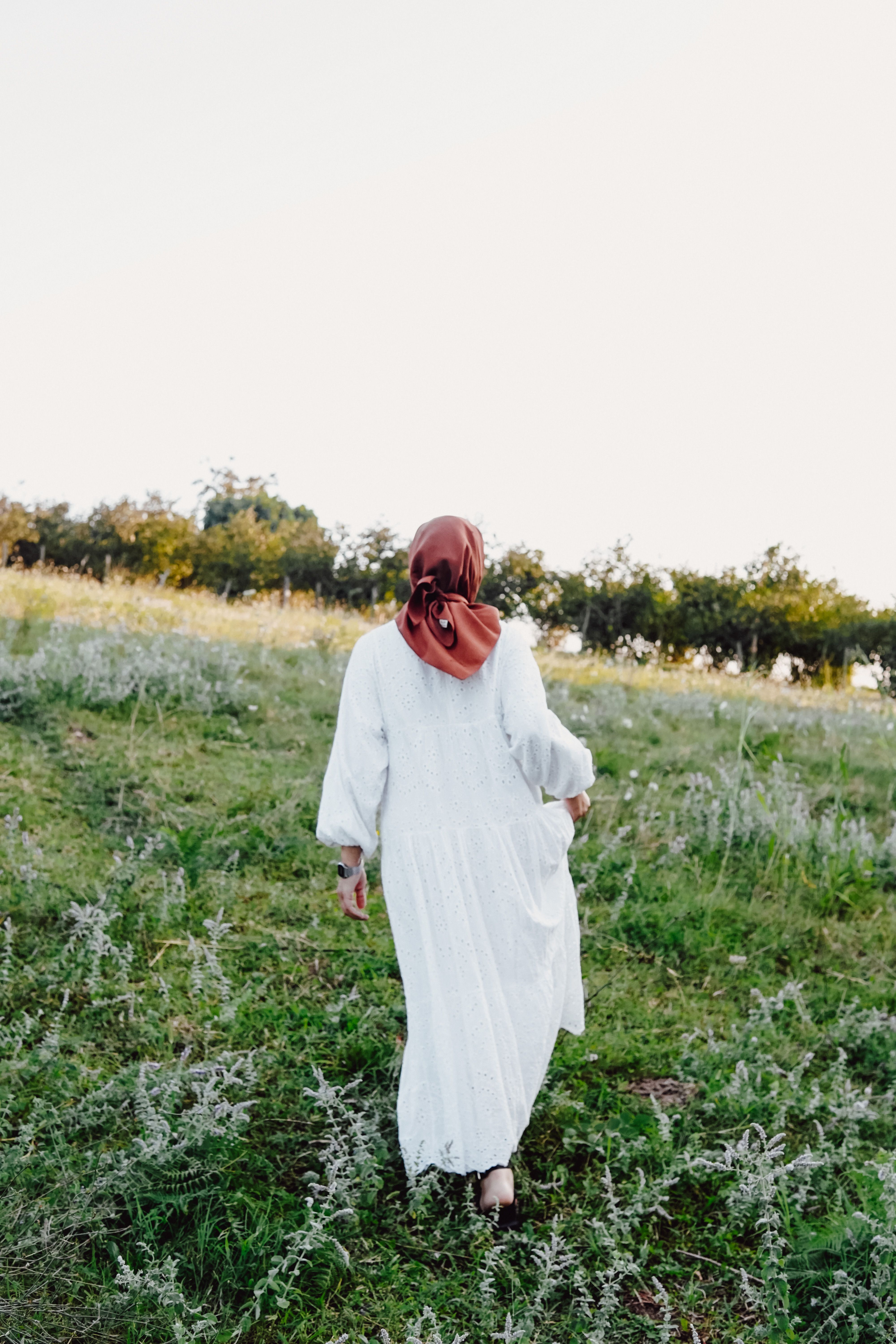 Woman in Hijab and White Clothes Walking on Meadow · Free Stock Photo