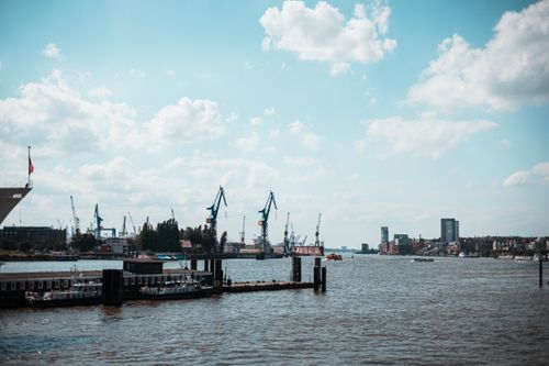 Free Explore the bustling Hamburg harbor with cranes and ships under a bright sky. Stock Photo
