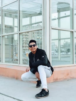 时尚年轻人自信地蹲在城区，展露现代风格和温暖微笑