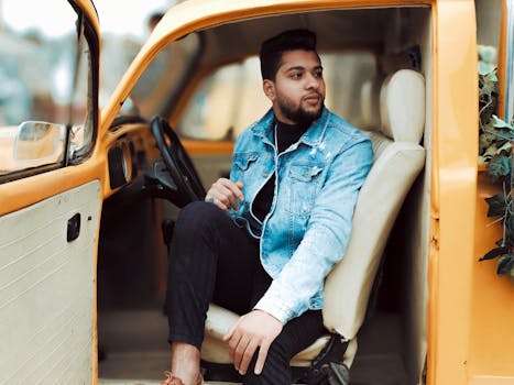 一位年轻人坐在一辆黄色古董车里，在户外享受轻松的时刻