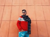 一位戴着太阳镜和围巾的时尚年轻人站在城市背景下，非常适合时尚和生活方式概念