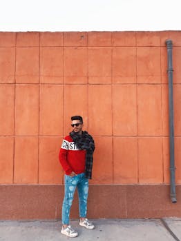 时尚的年轻人穿着时尚服装靠在城墙上