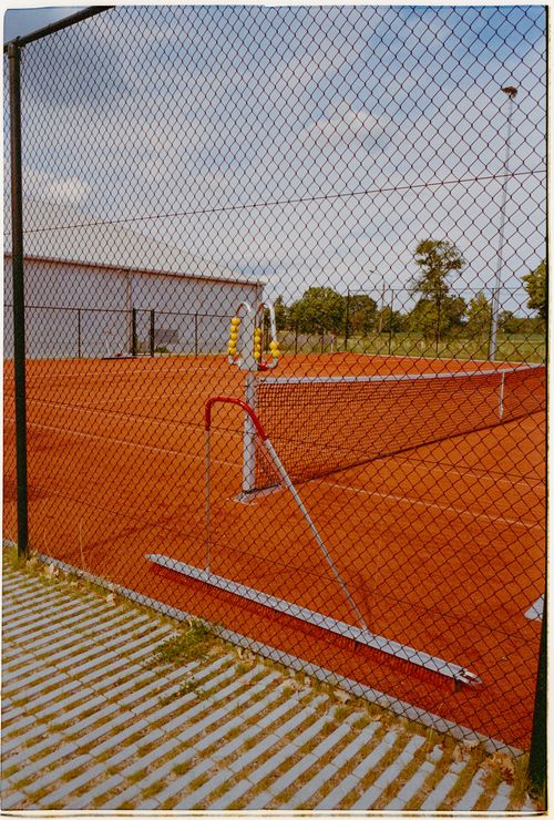 Free A clay tennis court with net and fence on a sunny day, perfect for sports activities. Stock Photo