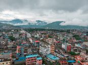 Explore a stunning aerial view of Pokhara, Nepal with vibrant urban architecture and mountainous backdrop.