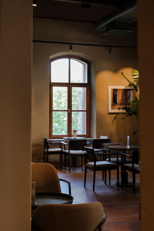 Free Stylish restaurant interior with wooden furniture and large window providing natural light. Stock Photo