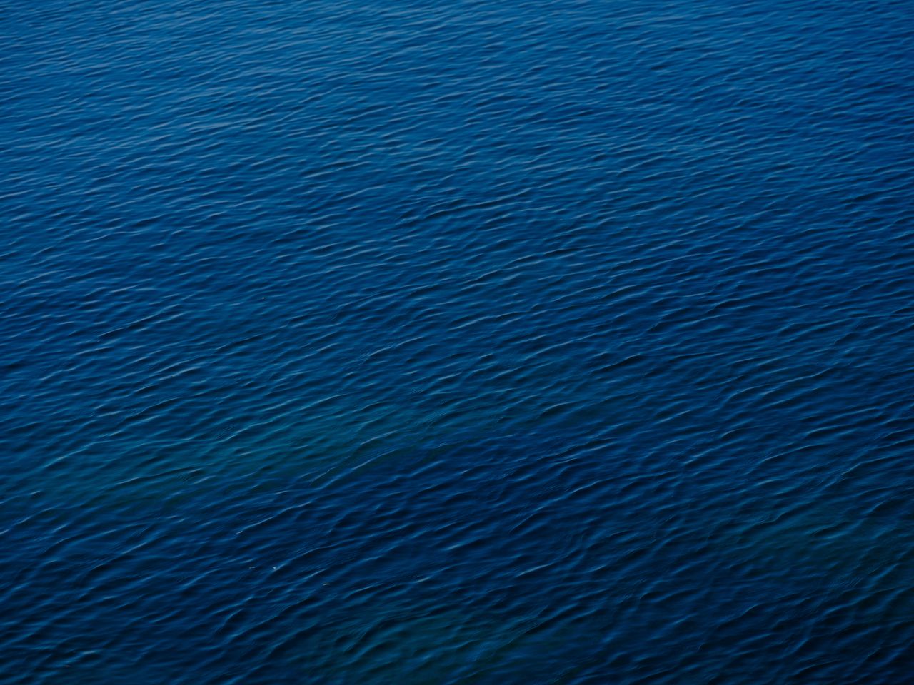 a serene aerial view of blue ocean water with gentle waves and a deep