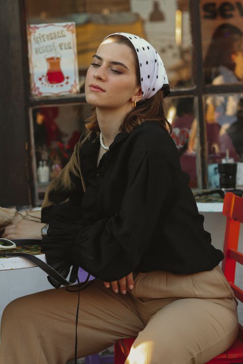 Free Serene woman seated in a vibrant urban cafe, embracing a calm moment of relaxation. Stock Photo