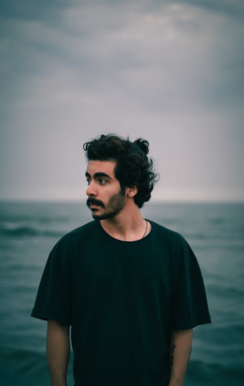 Man in T-shirt Standing on Sea Shore