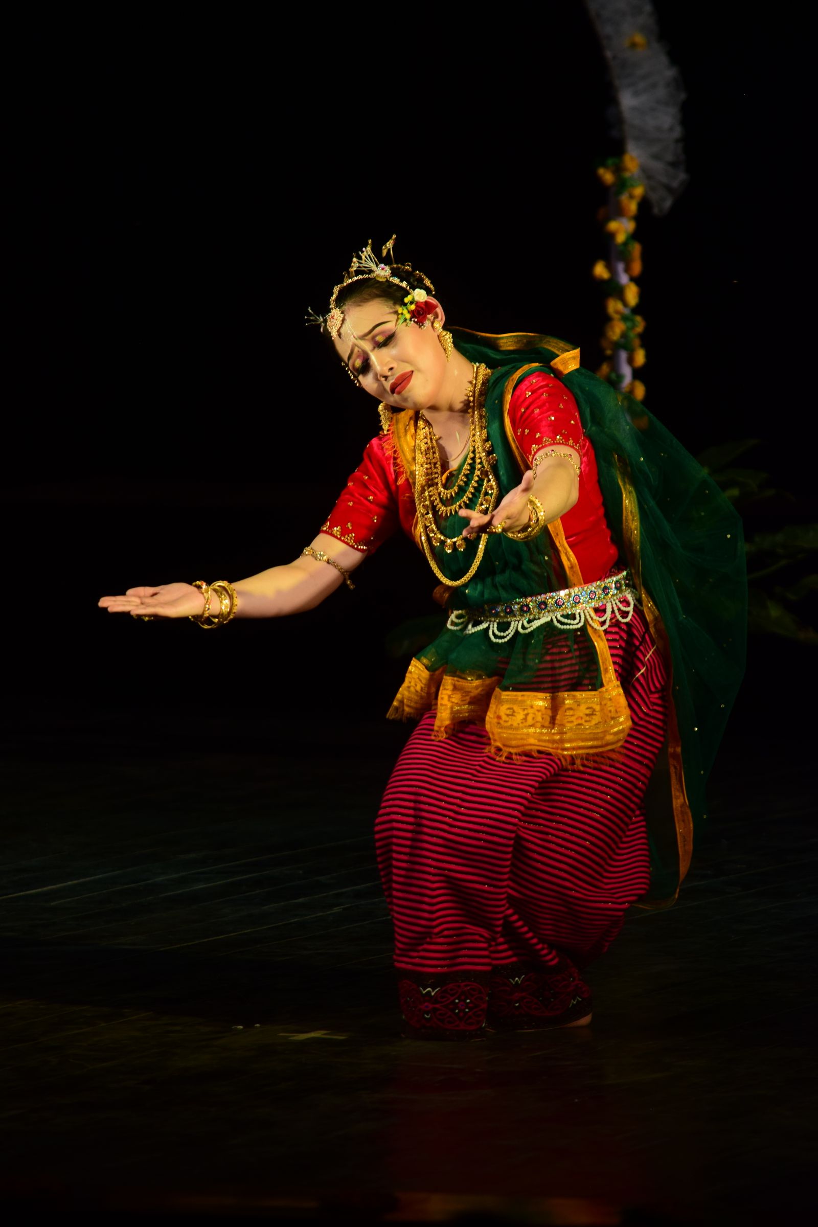 A classical Indian dancer in a colourful costume performing on stage