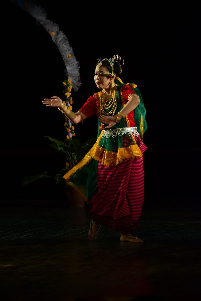 A woman performing a traditional Indian dance on stage in colourful attire