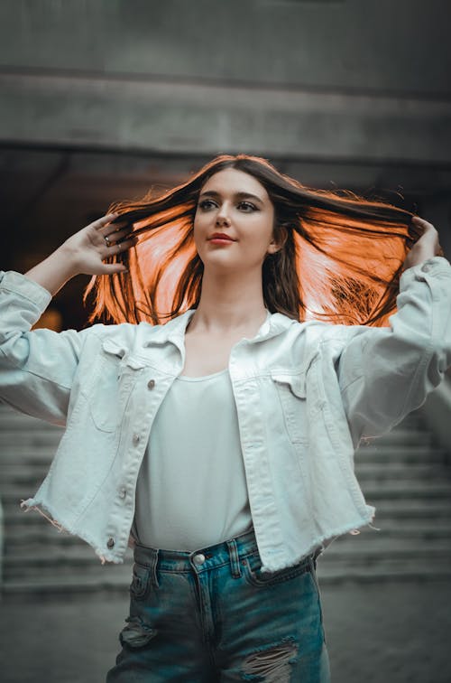 Young Woman Standing Outside and Fixing Her Hair 