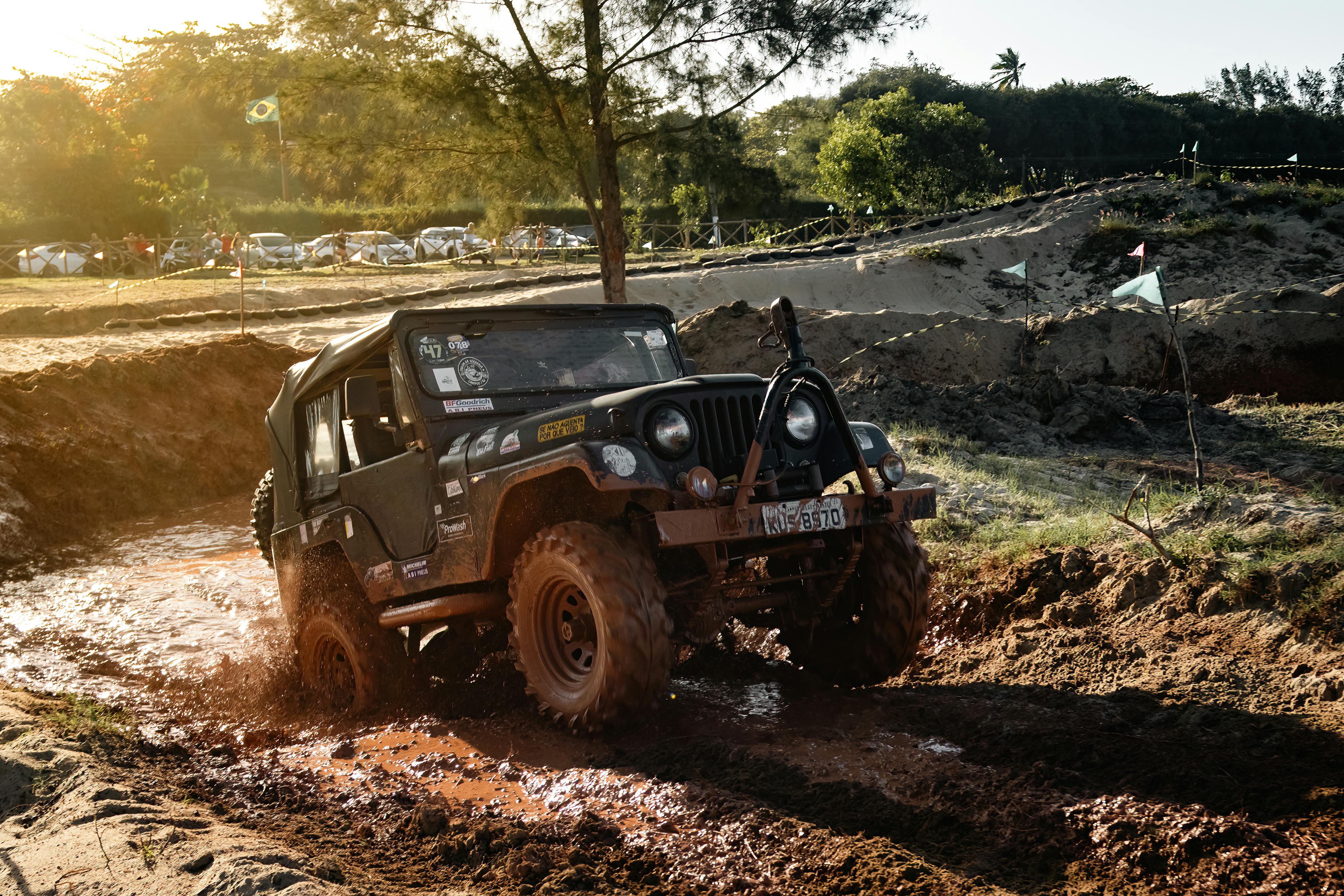 A rugged Jeep conquers muddy trails during an off-road adventure in a sunny landscape.