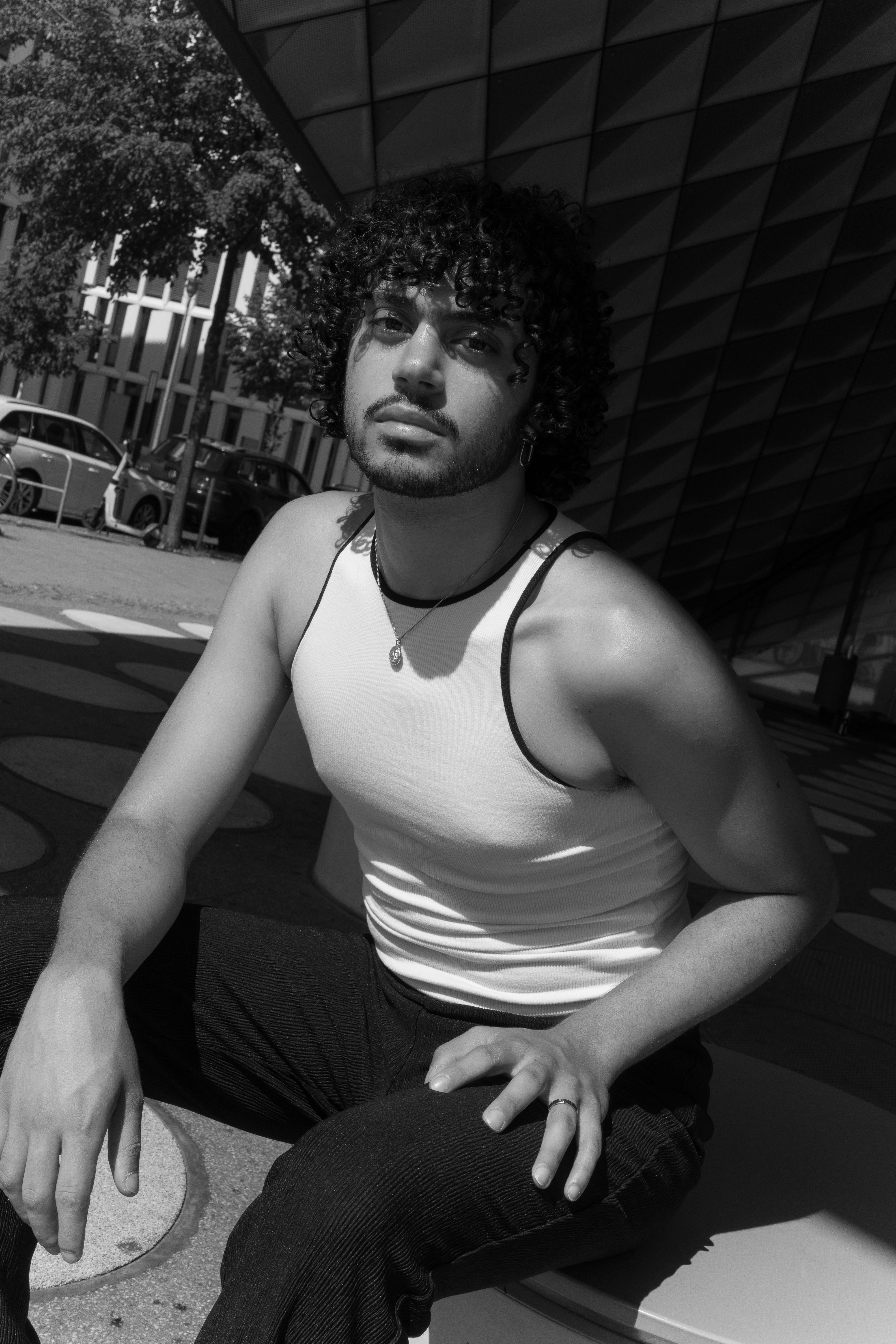 A young man poses confidently in a modern urban environment, highlighting fashion and style.