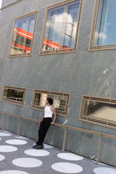 Man standing in urban setting, modern architecture, city vibes.