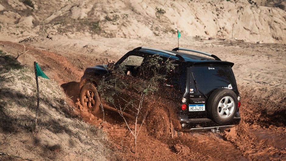 SUV drives through muddy off-road trail, showcasing vehicle durability and adventure.