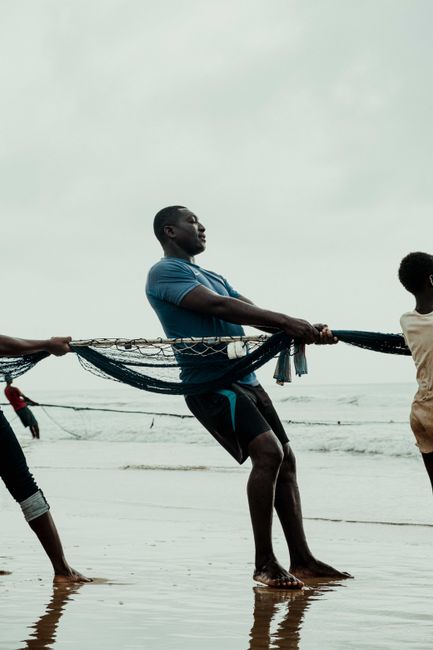 Group of men pulling a fishing net on the beach in Kumasi, Ghana.