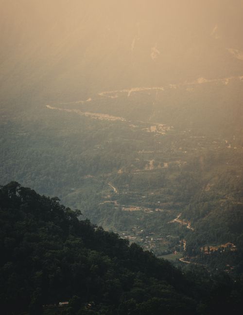 Free A tranquil view of a mountain valley at sunrise, enveloped in gentle mist and fading light. Stock Photo